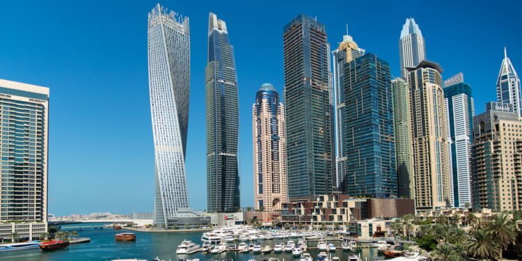 Vista panorâmica dos arranha-céus da Dubai Marina, iates e barcos atracados no píer do calçadão da Dubai Marina, com o Cayan Tower - depositphotos.com / SeaRain