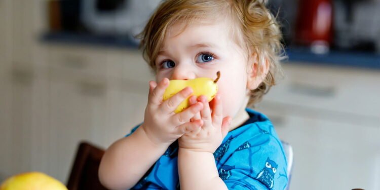 Criança comendo fruta - Créditos: depositphotos.com / romrodinka