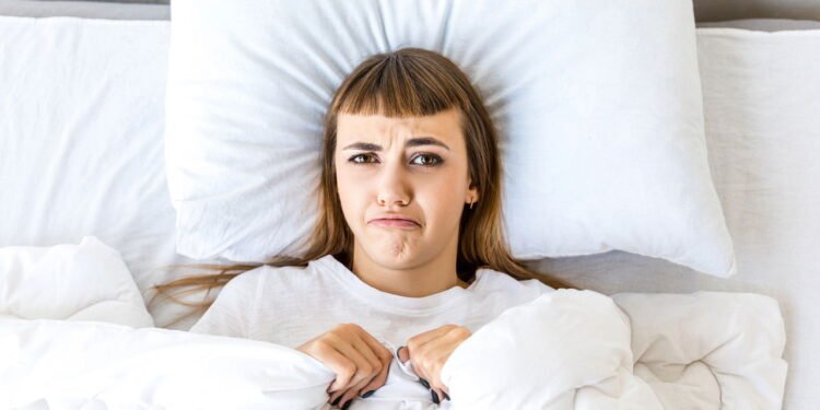 Pessoa deitada no travesseiro com expressão engraçada // Créditos: depositphotos.com / IraGirich