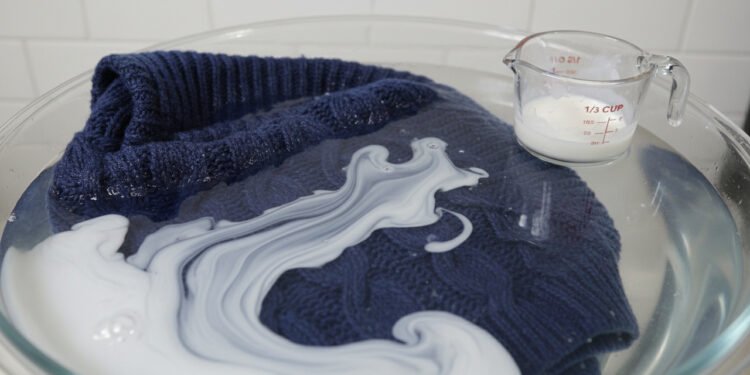 A técnica simples de imersão com 1/3 de xícara de condicionador que relaxa as "escamas" do tecido, desfaz a feltragem da máquina e recupera o tamanho original da sua roupa de lã favorita