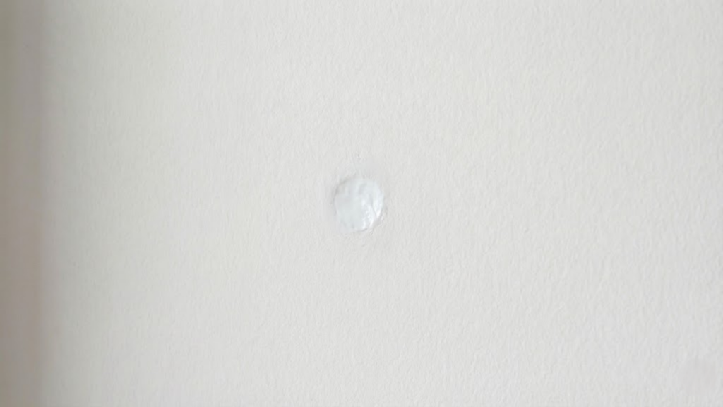 Pasta de dente branca usada para disfarçar pequenos furos de prego em paredes claras