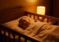 Bebê dormindo profundamente em berço iluminado apenas por uma luz amarela suave