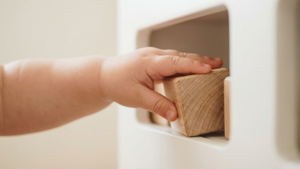 Prateleiras de madeira baixas com objetos organizados ao alcance das mãos de uma criança pequena