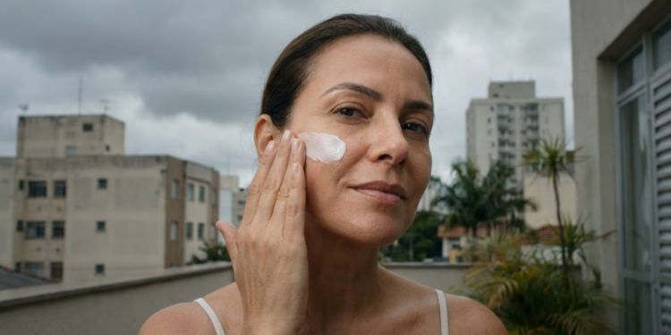 Mulher brasileira sob céu nublado aplicando protetor com confiança