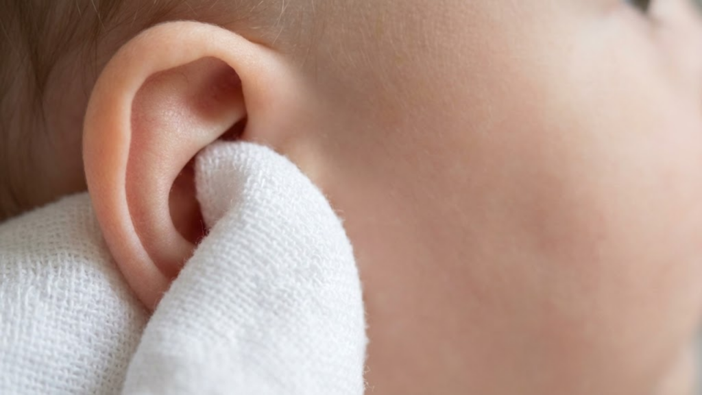 Macro detalhado da toalha de fralda limpando a parte externa da orelha