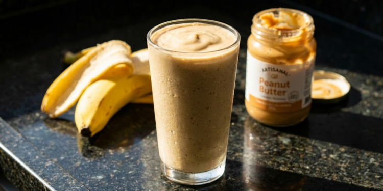 Vitamina cremosa em destaque com luz solar vibrante e ingredientes ao fundo.