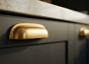 Puxador de armário dourado e luxuoso em cozinha iluminada.