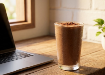 Copo de vitamina cremosa de cacau na mesa de trabalho com notebook