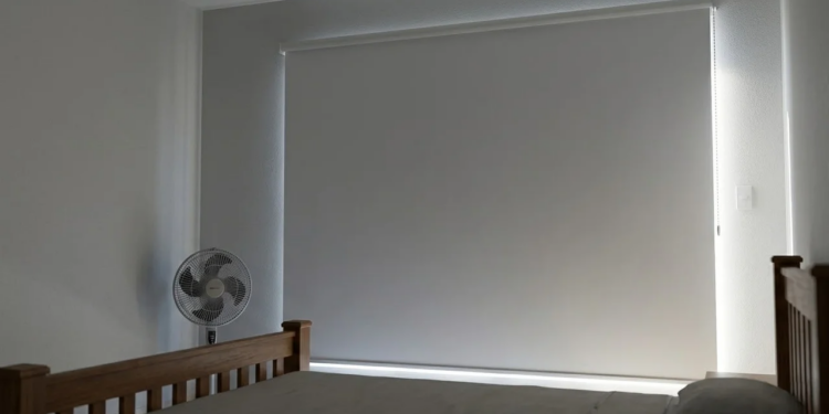 Quarto fresco e escuro com persiana rolô bloqueando o sol forte