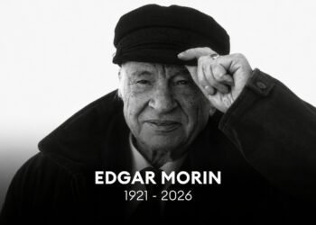 Retrato em preto e branco do filósofo Edgar Morin usando uma boina e tocando a aba com a mão esquerda. Na parte inferior, há o texto centralizado "EDGAR MORIN 1921 - 2026" em letras brancas sobre fundo escuro.