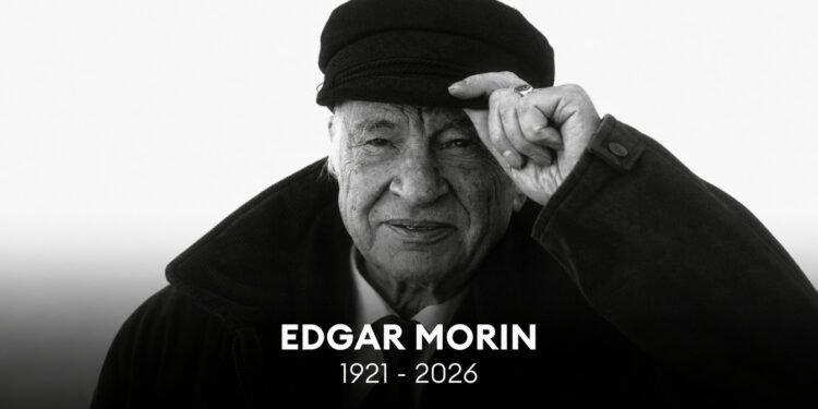 Retrato em preto e branco do filósofo Edgar Morin usando uma boina e tocando a aba com a mão esquerda. Na parte inferior, há o texto centralizado "EDGAR MORIN 1921 - 2026" em letras brancas sobre fundo escuro.
