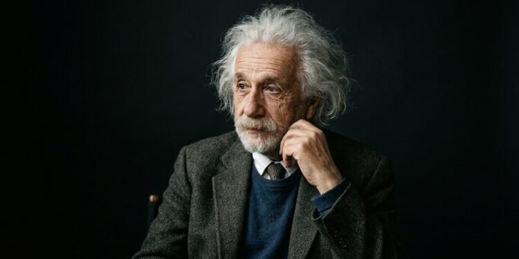 Retrato de Albert Einstein com expressão pensativa, cabelos brancos característicos e vestindo um paletó de tweed.
