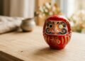 Boneco japonês daruma vermelho sobre superfície de madeira em luz suave