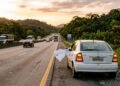 Carro parado no acostamento de rodovia com pano branco amarrado na janela do motorista