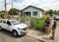 Fiscais da prefeitura inspecionando jardim com grama alta em residência durante operação de fiscalização urbana.