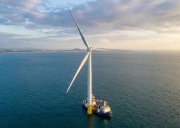 Maior turbina eólica offshore do mundo erguendo-se do mar com navio pequeno ao lado mostrando a escala colossal