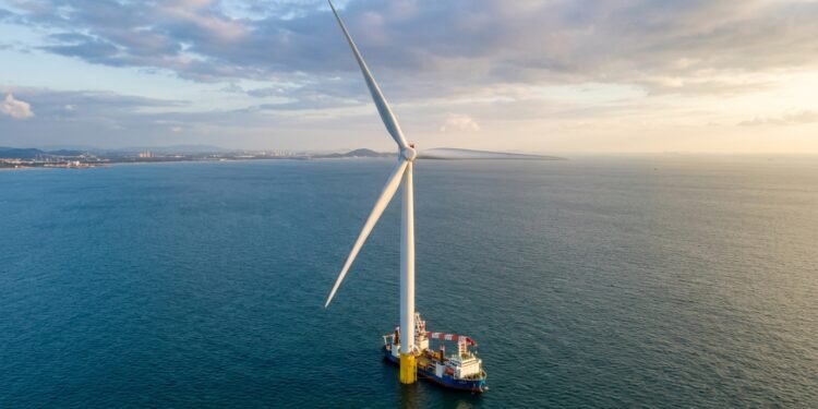 Maior turbina eólica offshore do mundo erguendo-se do mar com navio pequeno ao lado mostrando a escala colossal