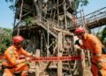 Bombeiros isolando uma grande casa na árvore de madeira com faixa de interdição por risco de incêndio.