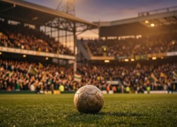 Bola de futebol no gramado de um estádio lotado ao entardecer, em clima de homenagem