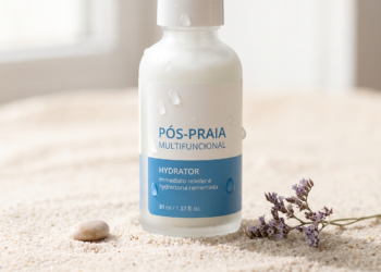 Frasco de produto pós-praia multifuncional sobre areia clara, com gotas de água, ao lado de uma pequena pedra e flores secas, destacando a hidratação da pele.