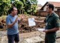 Fiscal ambiental autuando morador diante de terreno com árvores cortadas.