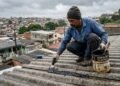 Mãos com luva aplicando cimento plástico com espátula sobre trinca em laje de concreto
