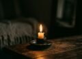 Chama de vela acesa iluminando suavemente um ambiente escuro e intimista