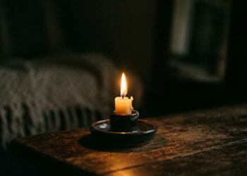 Chama de vela acesa iluminando suavemente um ambiente escuro e intimista