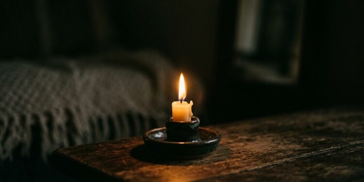 Chama de vela acesa iluminando suavemente um ambiente escuro e intimista