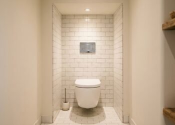 Vaso sanitário branco suspenso instalado em nicho revestido por azulejos, ilustrando a separação funcional de ambientes em banheiros.