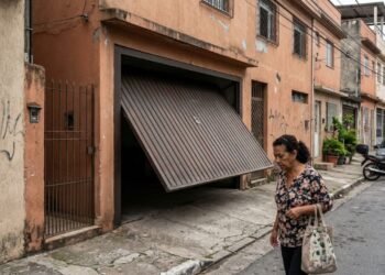 Morador instala portão eletrônico basculante que projeta 1 metro para fora da calçada ao abrir, atingindo pedestres que passam pelo local; a prefeitura aplica multa e notifica o proprietário para alterar o mecanismo de abertura por risco de acidentes.