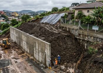 Proprietário despeja 15 caminhões de terra para nivelar o lote em relação à rua, usa o muro simples de alvenaria do vizinho como contenção sem fazer estrutura de arrimo e o muro cede sob a pressão da terra molhada após a primeira chuva forte