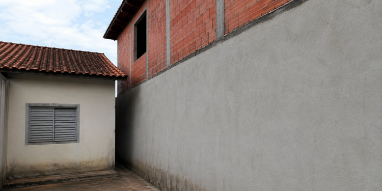 Morador constrói um segundo andar colado ao muro da divisa, cobrindo totalmente as janelas da casa ao lado e deixando a residência vizinha sem luz natural e ventilação