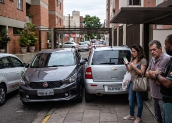 Morador irritado com carro mal estacionado trava o veículo do vizinho propositalmente na garagem de gaveta e ignora o interfone. A polícia enquadra a conduta criminalmente. O juiz o condena a pagar danos morais e reembolsar o táxi da vítima, configurando o ato como exercício arbitrário das próprias razões. 
