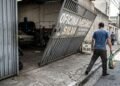 Oficina instala portão basculante automático de alta velocidade que avança 1,20 m sobre a calçada ao abrir sem avisadores sonoros, atingindo pedestres de surpresa; a fiscalização exige a instalação imediata de sinalização