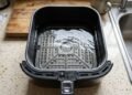 Colocar água no fundo da gaveta da air fryer: para que serve o truque simples que impede a fumaça de gordura queimada na cozinha