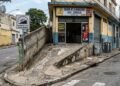 Lanchonete reforma a entrada do estabelecimento e cria uma rampa de concreto sobre o passeio público sem aprovação da prefeitura, impedindo a passagem de cadeirantes; o órgão de posturas autua a loja em R$ 2.400 e exige a demolição da estrutura conforme a NBR 9050