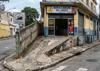 Lanchonete reforma a entrada do estabelecimento e cria uma rampa de concreto sobre o passeio público sem aprovação da prefeitura, impedindo a passagem de cadeirantes; o órgão de posturas autua a loja em R$ 2.400 e exige a demolição da estrutura conforme a NBR 9050