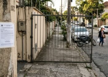 Morador troca o portão social da residência por um modelo que abre para o lado de fora em 90 graus, bloqueando totalmente o passeio público sempre que alguém entra ou sai do imóvel; a prefeitura aplica auto de infração exigindo a inversão do sentido de abertura para o interior do lote