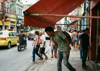 Lanchonete instala toldo retrátil com braços articulados que desce até 1,60 m de altura na calçada e obriga os pedestres a irem para o asfalto em avenida movimentada; a fiscalização de posturas autua o comércio com multa de R$ 1.800 e exige a readequação da altura mínima