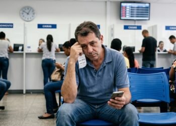 Cliente passa quase 2 horas esperando atendimento em agência bancária para resolver bloqueio de conta, descobre que a legislação municipal limita o tempo de espera e permite autuação pelo Procon, mas indenização por dano moral depende de circunstâncias adicionais além da demora