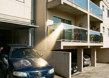 Morador instala fechamento de varanda com vidros espelhados para bloquear o sol, o reflexo concentrado queima a pintura do carro do vizinho parado na garagem ao lado e a disputa vai parar no Juizado Especial Cível