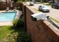 Vizinho coloca câmera sobre o muro para monitorar carros na rua, mas lente também alcança piscina e área de lazer da casa ao lado; proprietário exige reposicionamento do equipamento