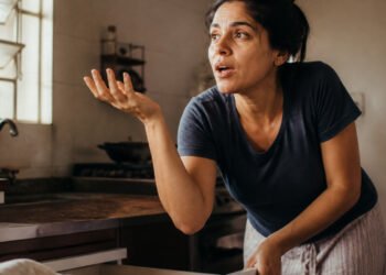 Mulher fala sozinha enquanto procura algo na cozinha