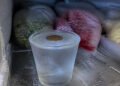 Moeda sobre o copo de água congelada no freezer