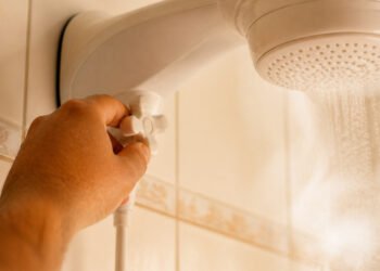 Mão abre o registro antes de ligar o chuveiro