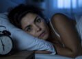 Mulher acordada na cama minutos antes do despertador tocar