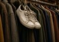 Par de tênis brancos usados pendurado numa loja de roupas de segunda mão