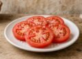 Fatias de tomate com sal grosso soltando suco num prato