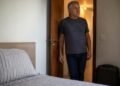 Aposentado observa o quarto extra preparado para hóspedes no apartamento
